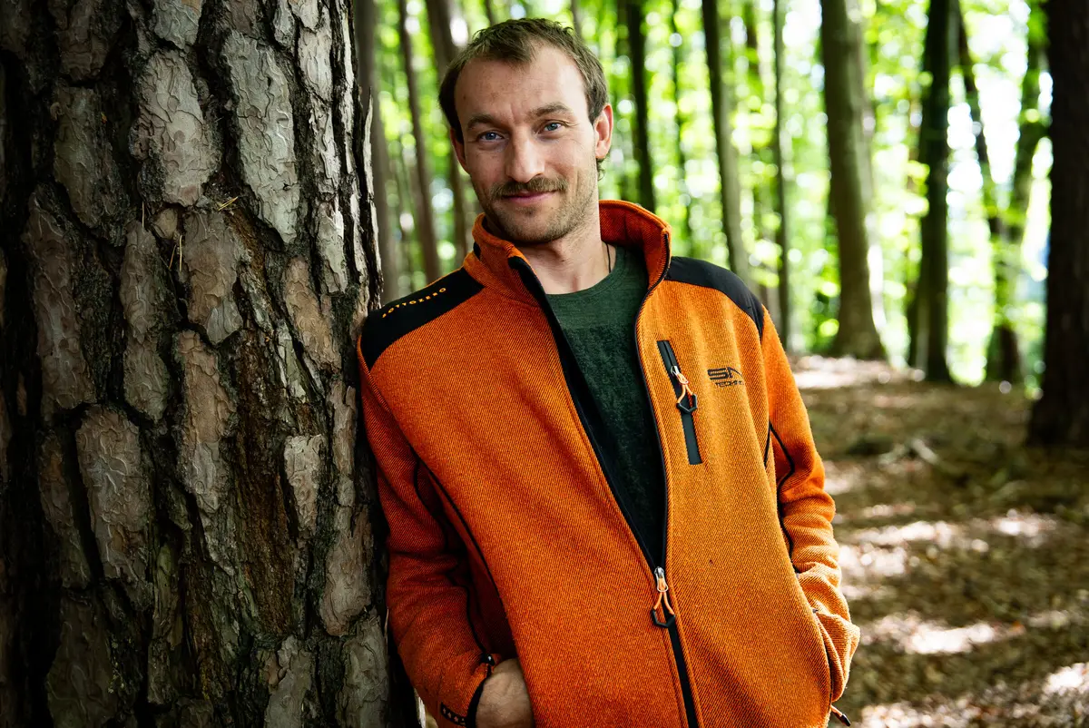 Michael Stellbauer lehnt lächelnd an einem Kiefernstamm